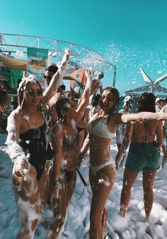 several women in bathing suits are throwing water at each other on the snow covered beach