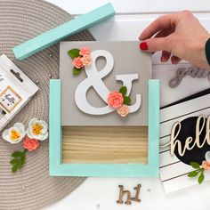 a person is holding up a paper cutout with the letter e and flowers on it