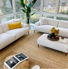 a living room filled with white couches and chairs next to a large glass window