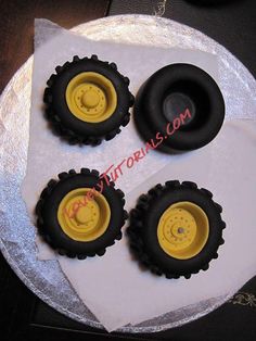 four black and yellow wheels on top of a white cake with silver foil around it