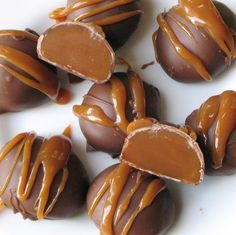 chocolates with caramel drizzled on them sitting on a white plate