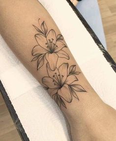 a black and white flower tattoo on the left arm, with flowers in blooming