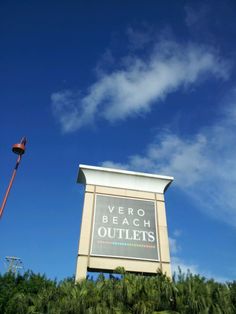 a very tall sign sitting in the middle of a lush green field under a blue sky