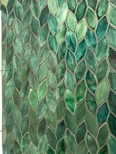 a bathroom with green tiles on the wall and tile flooring that looks like hexagonals