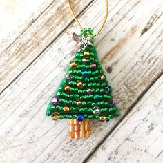 a beaded christmas tree ornament hanging on a wooden surface