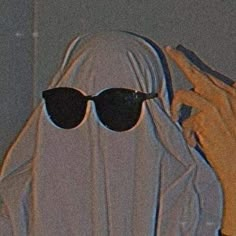 a woman wearing sunglasses and a white veil covering her face with the hood pulled back