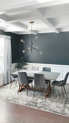 a dining room table with chairs and a chandelier hanging from the ceiling above it