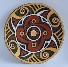 a decorative plate is shown on a white surface with red and black designs in the center