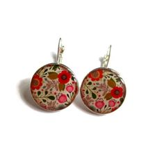 pair of earrings with red and green flowers on the front, sitting on a white surface