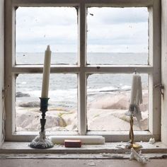 two candles sitting on top of a window sill