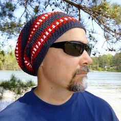 a man wearing sunglasses and a crocheted beanie looks off into the distance