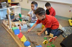 three children playing with wooden toys in a room