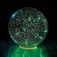 a green ball with stars on it sitting on a table in the dark, lit up