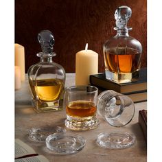 three glass decanters and two candles on a table