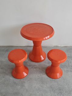 an orange table and two stools on concrete