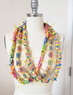 a white mannequin wearing a multicolored necklace with candy bars on it