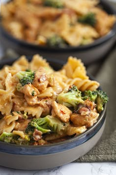 two bowls filled with pasta and broccoli on top of a table