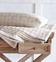 two pillows are sitting on top of an old wooden table with drawers and drawers underneath them