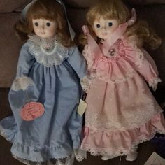 two dolls sitting next to each other on a couch