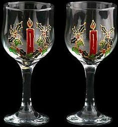 two wine glasses with candles and holly designs on the bottom one has a red candle