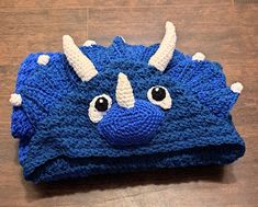 a crocheted blue and white hat with horns on the top, sitting on a wooden floor