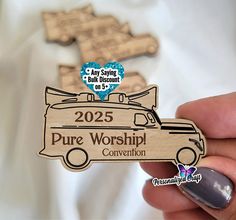 a person holding up a wooden magnet that says, 205 pure worship convention