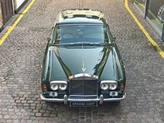 an old green car is parked on the street