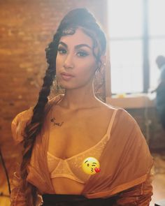 a woman with long hair wearing an orange shirt and holding a yellow smiley face sticker