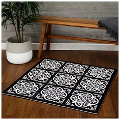 a black and white area rug on a wooden floor next to a potted plant