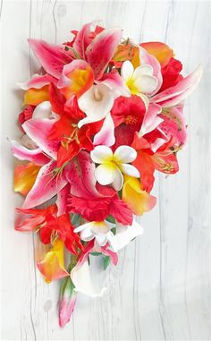 a bouquet of red and yellow flowers sitting on top of a white wooden table next to a wall