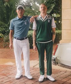 two men standing next to each other in front of a white car and palm trees