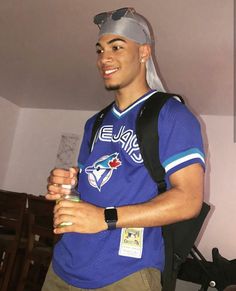 a man in a blue jersey holding a water bottle and wearing a silver head band