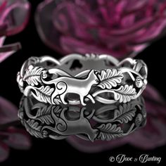 a silver ring with a horse on it's side and flowers in the background