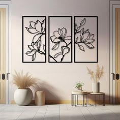 three black and white paintings hanging on the wall next to a vase with flowers in it