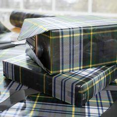 two wrapped presents sitting on top of each other in plaid wrapping paper and black ribbon