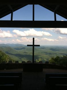 a cross on top of a hill with mountains in the background