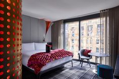 a bed room with a neatly made bed next to a window and a table in front of it