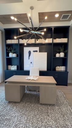 a modern office with built in bookcases and a chandelier above the desk