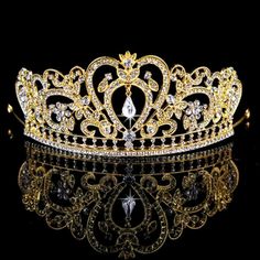 a gold tiara with crystal stones and pearls on the side, sitting on a black surface