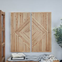 two wooden panels on the wall above a table with books and a potted plant