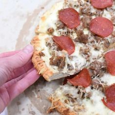 a person is taking a bite out of a pepperoni pizza with sausage and cheese