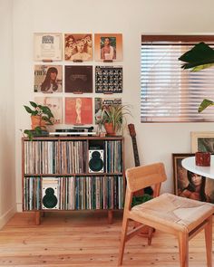 a room with various records on the wall and a wooden chair in front of it