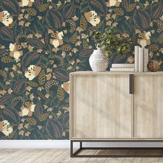 a cabinet with books on it in front of a wallpapered background that has flowers and leaves