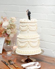 a wedding cake with a bride and groom figurine on top sitting on a table