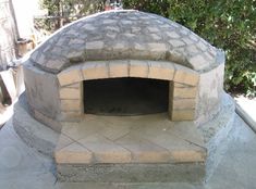 an outdoor brick pizza oven built into the side of a building with cement bricks on it