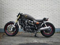 a motorcycle parked in front of a white brick wall with red rims on it