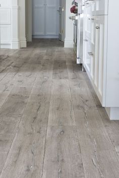 a kitchen with white cabinets and wood floors