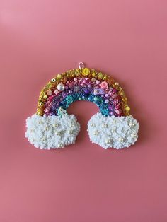 a rainbow brooch sitting on top of a pink table next to a white cloud