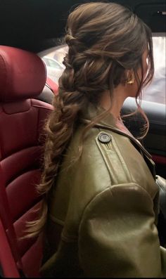 a woman sitting in the back seat of a car with her hair pulled into a braid