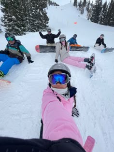 a group of people riding snowboards down a snow covered slope